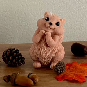 Bougie d'Automne Ecureuil artisanale, représentant un écureuil mignon entouré de pommes de pin, glands et feuilles d'automne, idéale pour une décoration chaleureuse et saisonnière.